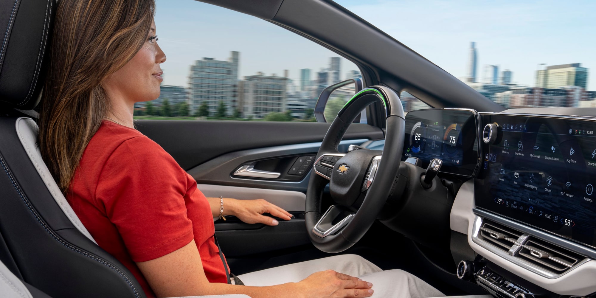 Une personne appuie sur l’écran du système d’infodivertissement du Chevrolet Equinox EV 2025 pendant qu’elle tient le volant de son autre main.