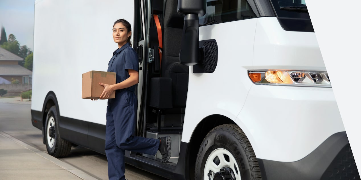Une employée du service de livraison de GM sort de la fourgonnette électrique Chevrolet BrightDrop 2025 en transportant une petite boîte.
