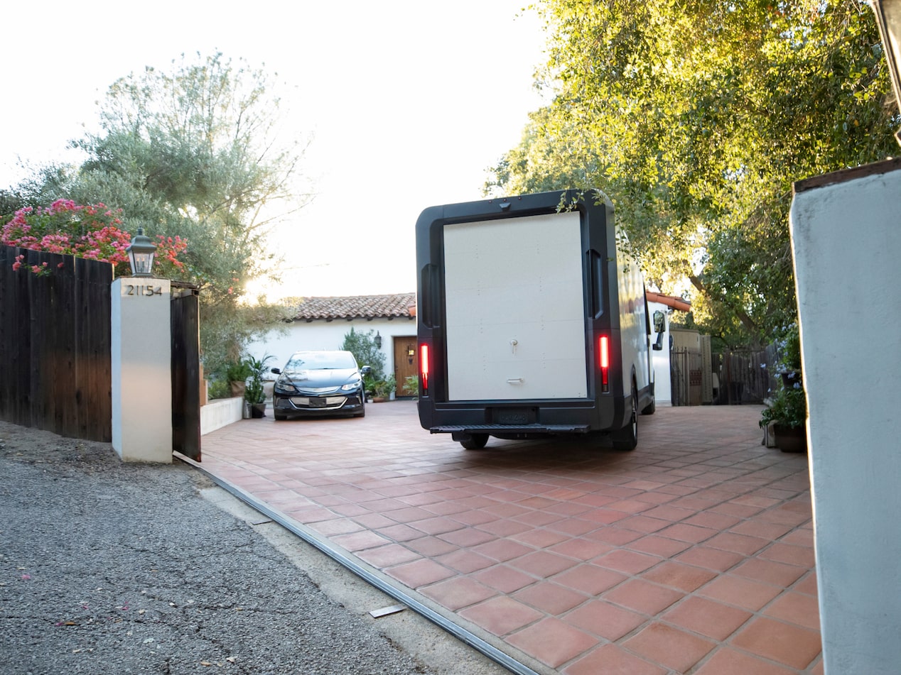 Vue arrière de la fourgonnette électrique Chevrolet BrightDrop 2025 qui arrive dans une entrée.