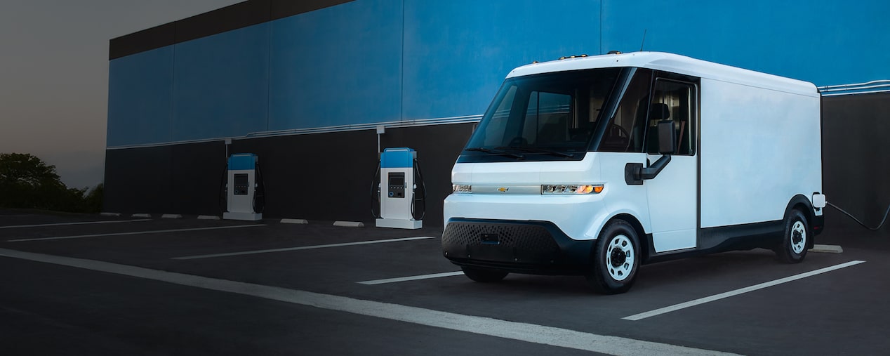 Une fourgonnette électrique Chevrolet BrightDrop stationnée seule à une borne de recharge de VÉ.