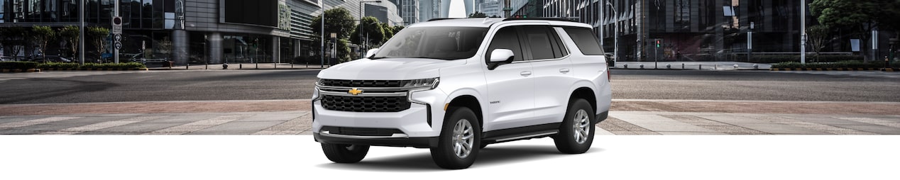 Vue latérale avant du Chevrolet Tahoe 2024 stationné dans un paysage urbain.
