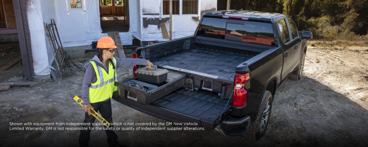 A construction worker placing a toolbox at the trunk bed of the 2024 Chevrolet Silverado 1500.