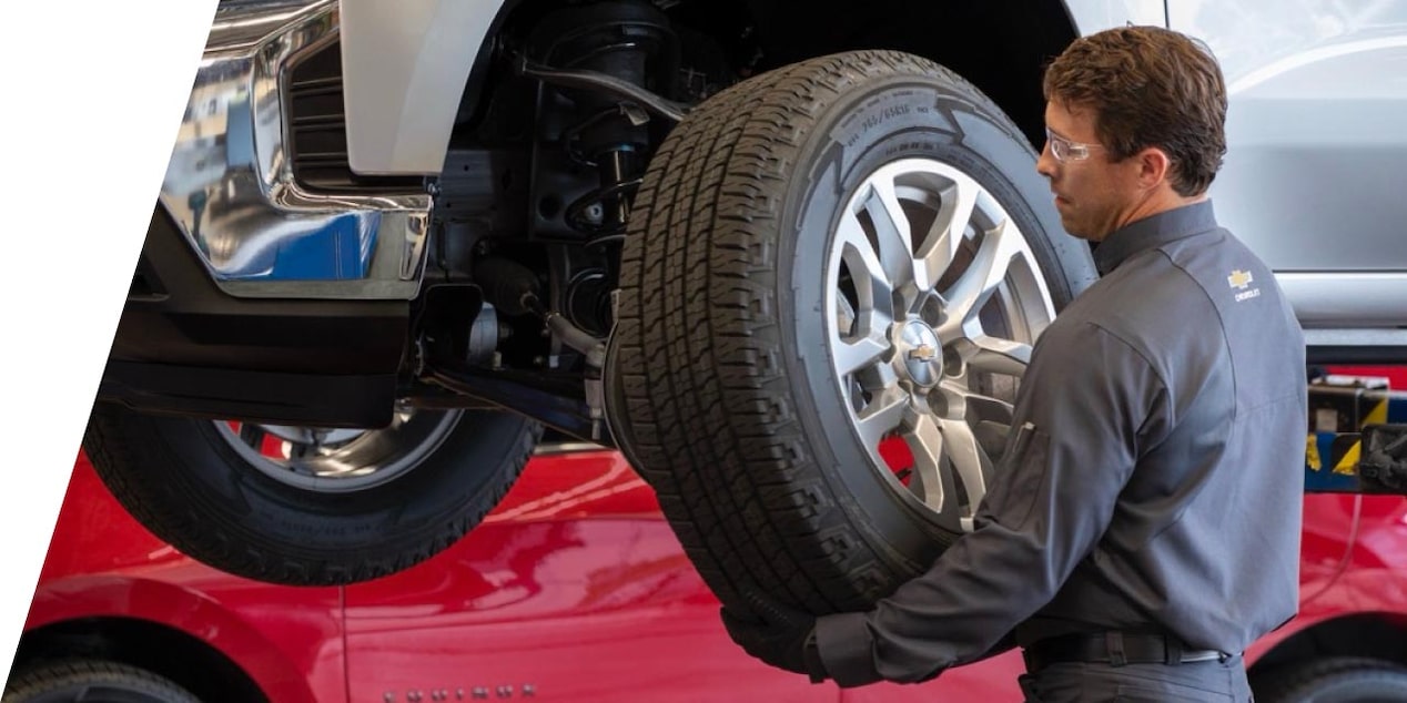 A car mechanic replacing a tire on a GM Envolve vehicle.