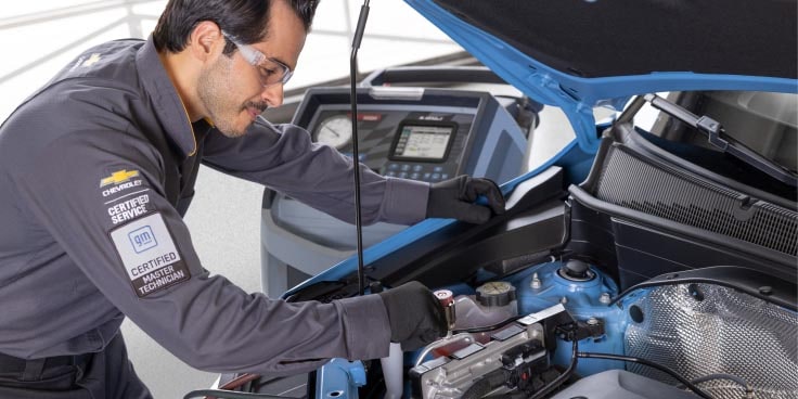A Car Mechanic making fixes on the hood section of a GM Envolve vehicle.