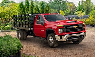 Véhicule avec l’aménagement camion à plateforme/à ridelles de GM Envolve stationné dans une zone bordée d’arbres.