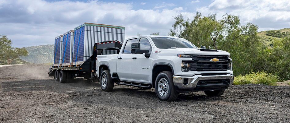 GM Fleet work truck towing a cargo trailer on a dusty road.