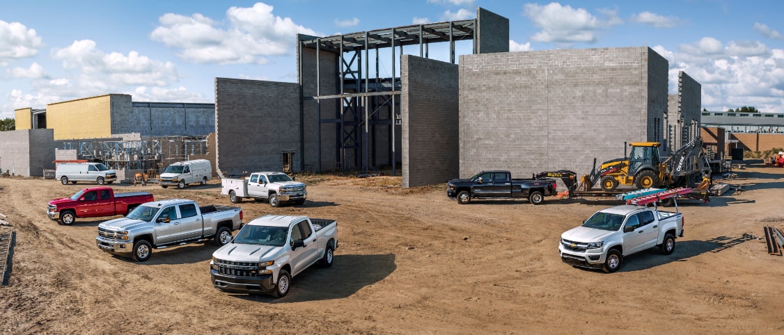 Plusieurs véhicules GM stationnés autour d’un chantier.