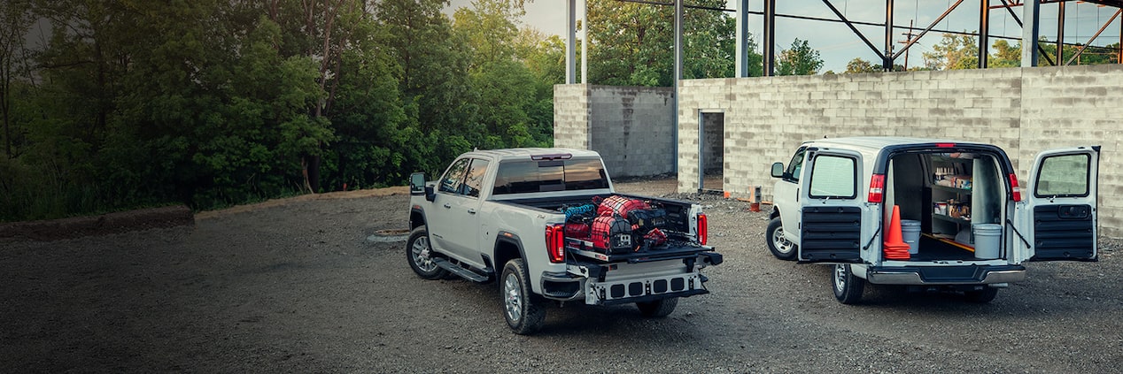 Two GM Envolve trucks parked on a job site.