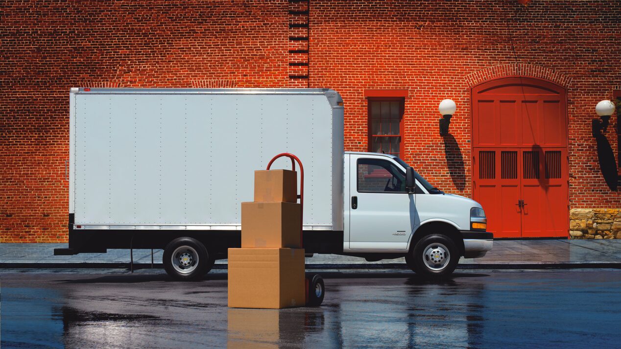 Side view of a GM Envolve Delivery truck parked near boxes.