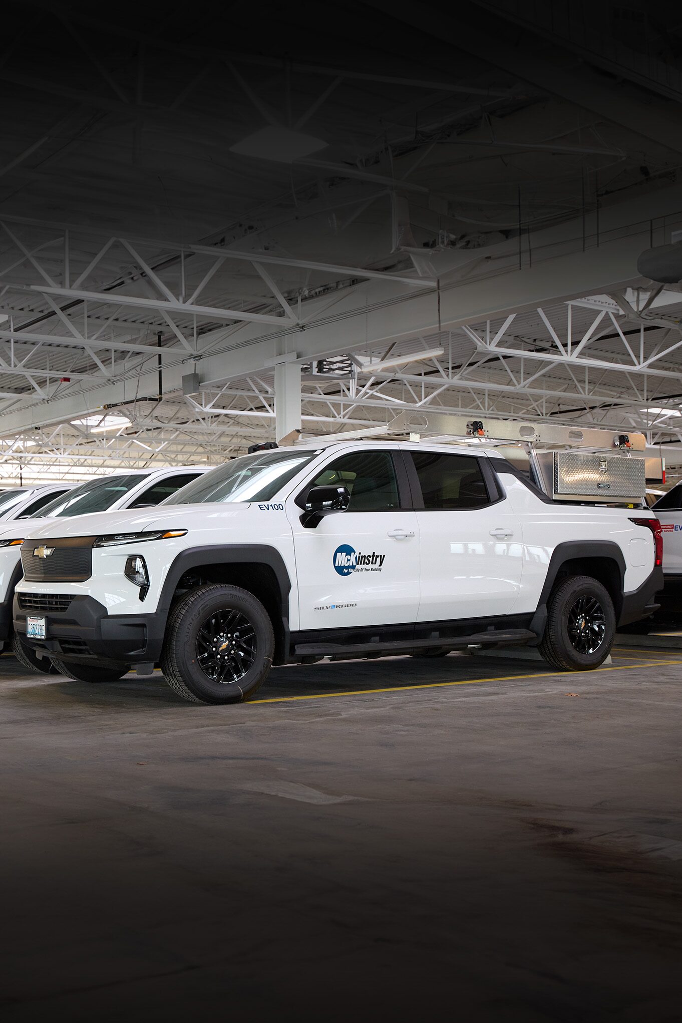 A white Chevrolet Silverado EV with a McKinstry logo on the door parked in a garage