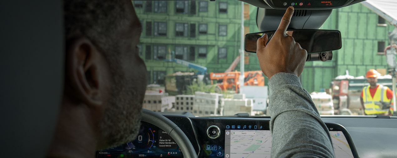 A driver pressing the OnStar button in their GM vehicle.
