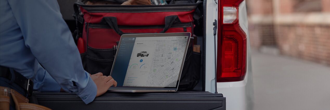 Someone Accesing OnStar Vehicle Insights from a laptop on their truck's tailgate.
