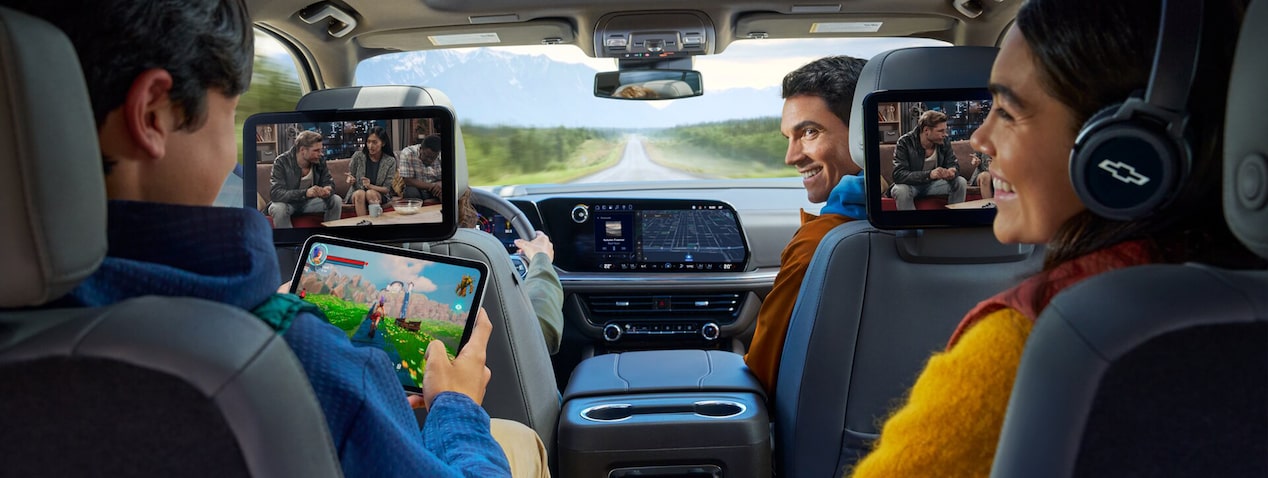 A family seated in a vehicle with the dad in the front passenger seat looking back at his kids.