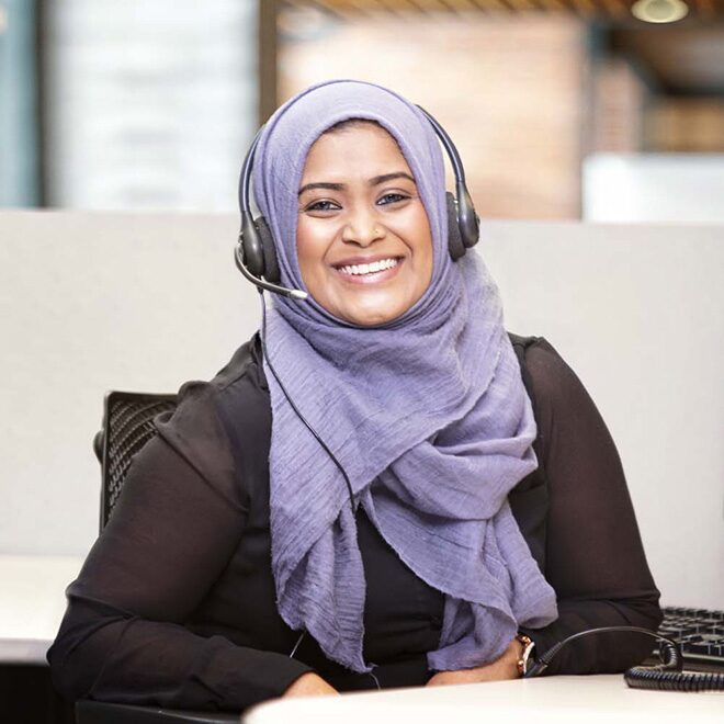 Une conseillère OnStar qui porte un hijab et un casque d’écoute sourit.