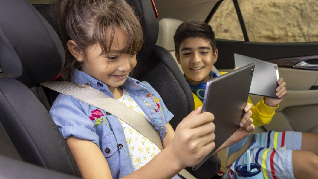 Deux enfants utilisent leur tablette pour accéder à la diffusion en continu haute définition d’OnStar.