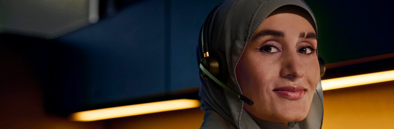 A female OnStar advisor looking towards the camera smiling while wearing her headset and hijab