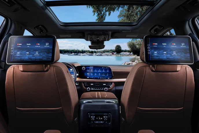 A shot from the passenger seat of a vehicle with displays attached to the front seats in front of a body of water.
