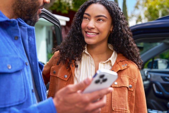 A man is showing something on his phone to a woman and she is smiling at him.