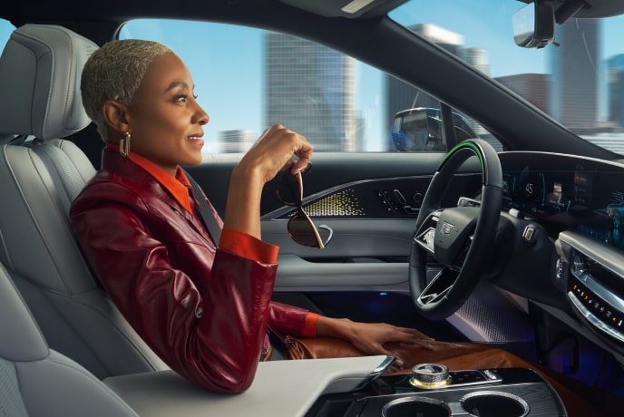 A Woman sitting in the driver’s seat of a self-driving vehicle holding her glasses.