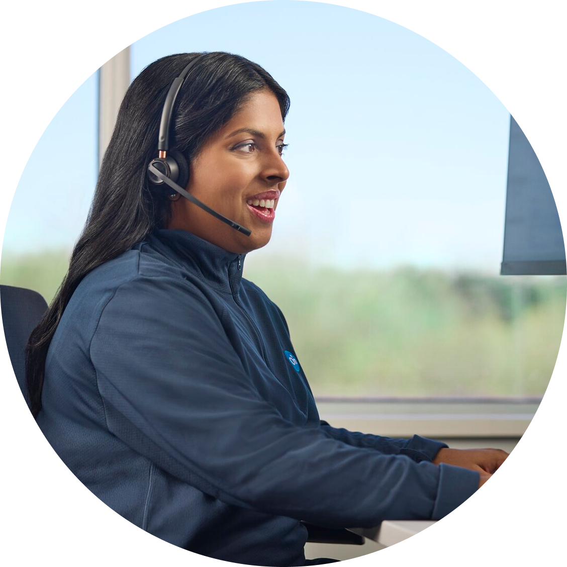 A side view of a female OnStar advisor smiling while looking at her computer and typing on her keyboard