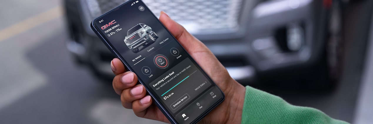 Hand Holds myGMC Mobile App in Front of Vehicle